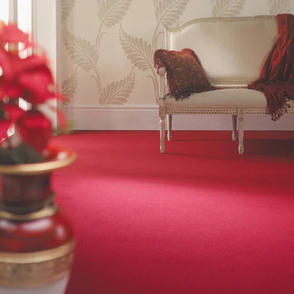 Rich red carpet with a classic cream chair and botanical wallpaper