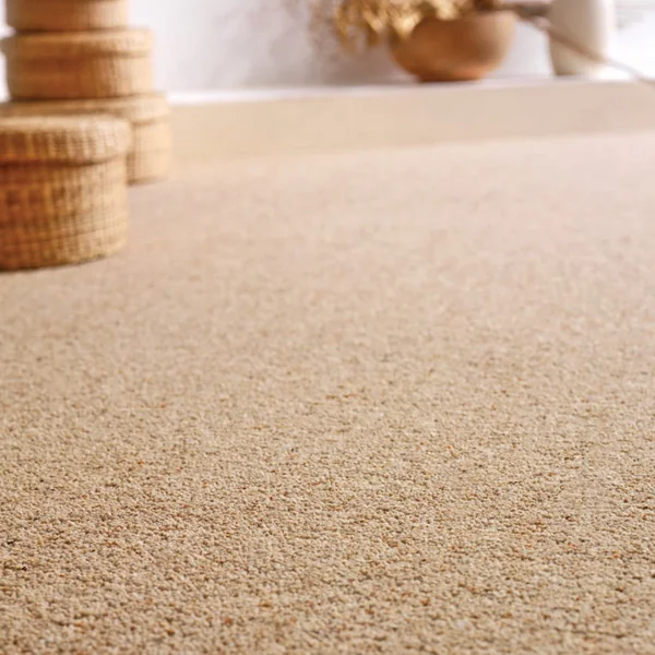 Warm oatmeal carpet beside a woven basket and an upholstered chair
