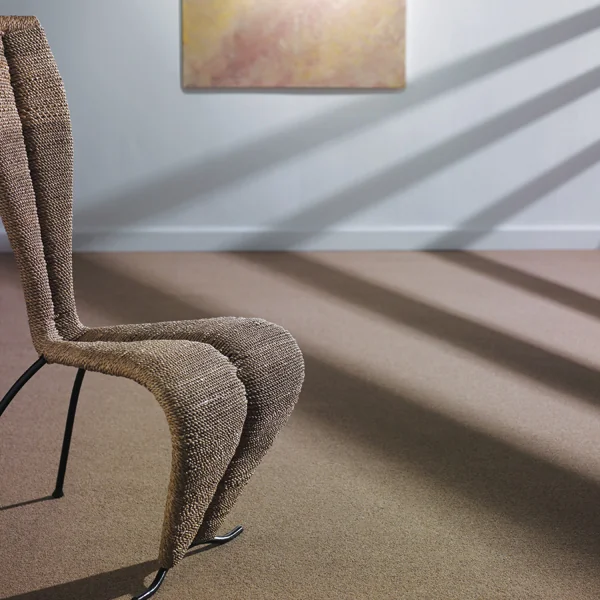 Grey carpet with a sculptural chair and soft afternoon shadows