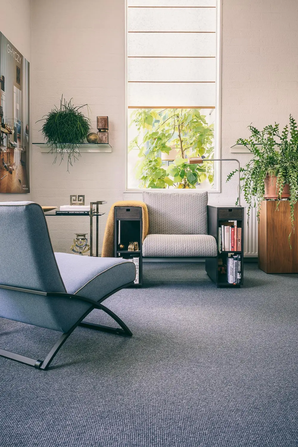 A blue-grey loop carpet in a bright room with a lounge chair, shelves and plants