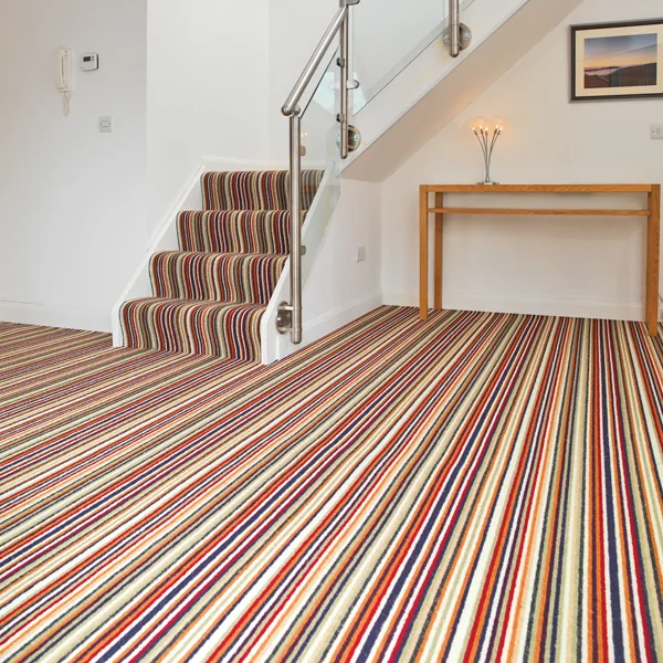A multicoloured striped carpet running across a hallway and up a staircase