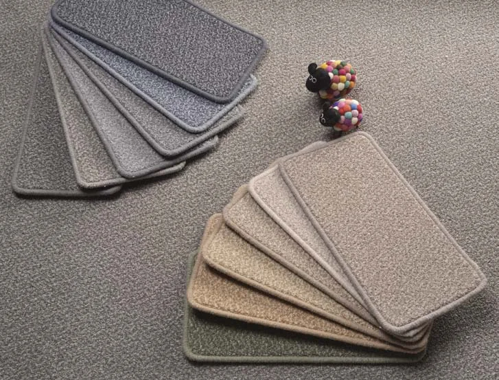 Two fans of carpet samples in greys, taupes and a soft green on a tweed carpet